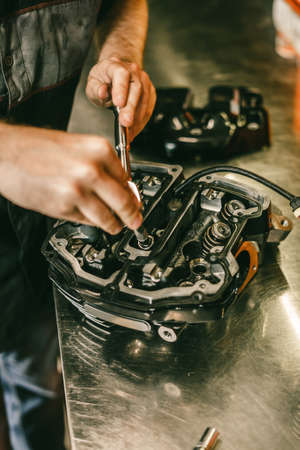 Closeup hands of motorcycle mechanic engine repair at service station. Handsome young man repairing motorcycle in repair shop.の写真素材