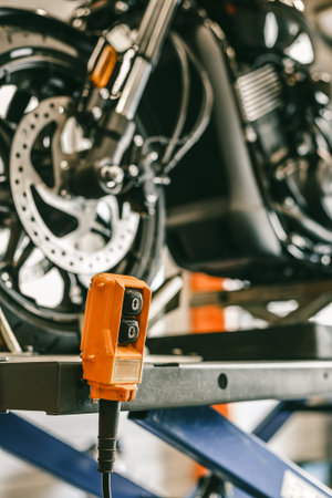 Closeup up down hydraulic controller switch on a lift with a motorcycle. Bike during maintenance,...
