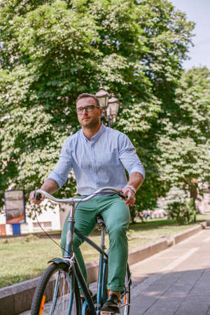 Businessman riding bicycle to work on urban street in morning. Lifestyle, transport, communication and people concept,の写真素材