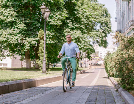 Businessman riding bicycle to work on urban street in morning. Lifestyle, transport, communication and people concept,の写真素材