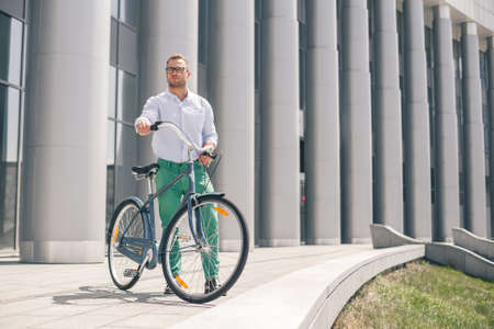 Handsome hipster enjoying city ride by bicycle. Businessman and his bicycle on city streets. The concept of the modern lifestyle of young men.の写真素材
