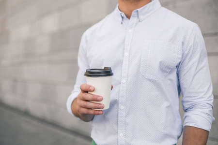 Closeup view of a hand of business man holding a coffee cup. A young man in a light blue shirt.の写真素材