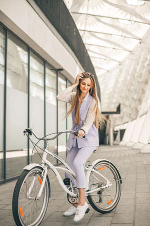 Full length shot of a beautiful young businesswoman with her bike going to work. Beauty with white vintage bike.の写真素材