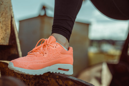 Closeup of a foot in a sneaker while doing sports on the street. Orange shoes on a metal rusty...