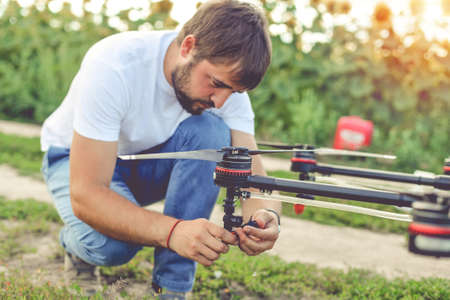 Young engineer preparing agriculture drone before flying on the sunflower field.の写真素材
