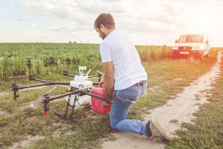 View from the back process of preparing agro drones for irrigation. A man agronomist pours liquid into a Octocopter .の写真素材