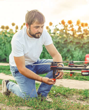 Young engineer preparing agriculture drone before flying on the sunflower field.の写真素材