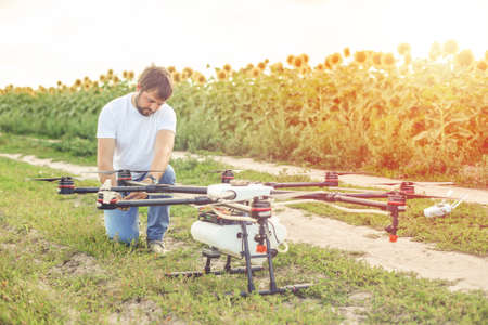 Young engineer preparing agriculture drone before flying on the sunflower field.の写真素材