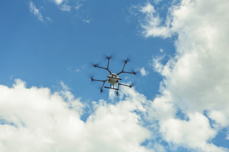 Hovering drone flies in blue sky and taking pictures of green hills. Professional agriculture drone...