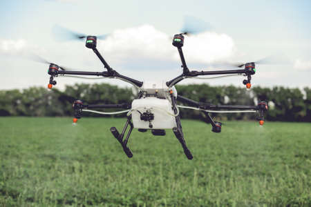 Agriculture drone spraying water or pesticides to grow over green field. Smart farming concept.の写真素材