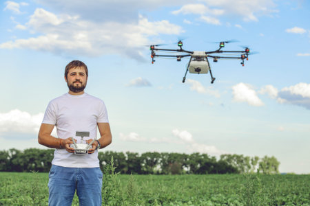 Portrait of a young male farmer with a professional drone against a green field background....