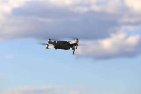 Quadcopter with camera flying on a clear sunny sky sunset background with nice lens flare.の写真素材