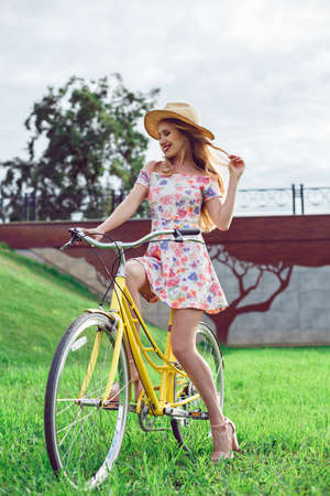 Young beautiful woman with yellow bicycle in a park. Active people spending time outdoors.の写真素材