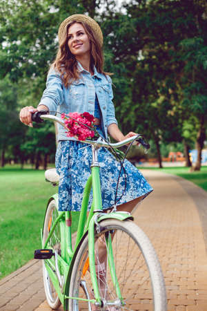 Young woman in a hat riding a bicycle in a parkの写真素材