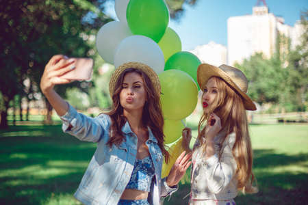 Young women do selfie with balloons in the park in the morning sun. Morning sun rays and active lifestyle concept.の写真素材