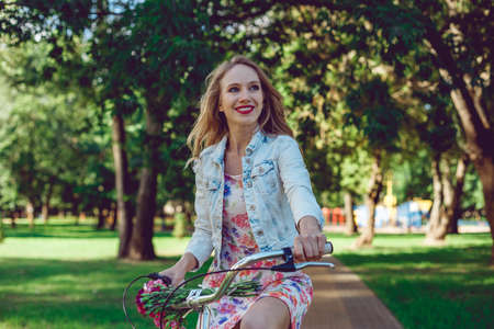 Portrait of happy woman biking in city park on bicycle. Beautiful girl on bike cycling outdoors in summer smiling of joy during outdoor activity.の写真素材