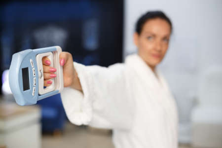Physiotherapy - beautiful woman making arm exercises. Woman holds in her hand a special device for measuring strength.の写真素材