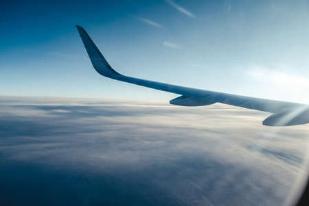 Airplain wing view thrue porthole in the skyの写真素材