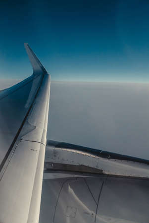Airplain wing view thrue porthole in the skyの写真素材