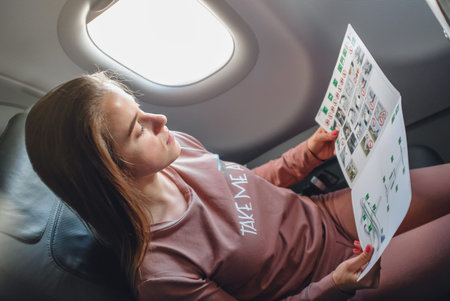 Girl is reading insructions in arplane near the window