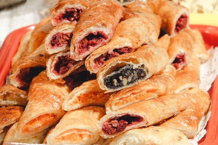 Puff pastry with cherry and poppy filling. Baking lies on a tray and is ready for sale.の写真素材