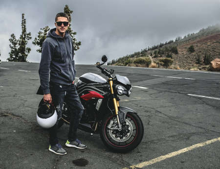 Rider stand on a mountain next to motorcycleの写真素材