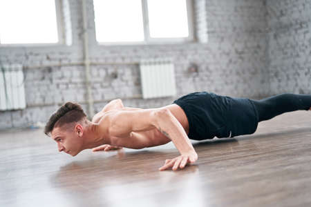Athletic young man doing push ups on the floor. Young man workout in fitness club.の写真素材