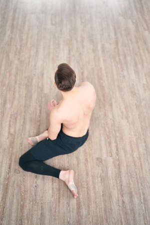 Handsome ballet dancer sitting on a splits. Warm up on the floor.の写真素材