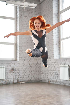 Young sport woman gymnastics doing jumping fitness exercise at sport gym.の写真素材