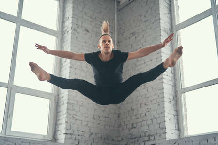 The young attractive modern ballet dancer in black jacket jumping over urban background.の写真素材