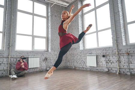 Young female dancer jumping and dancing in the gym. fashion ballet dancer. studio shotの写真素材