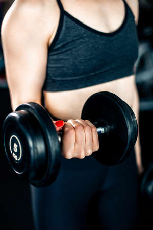 Girl doing bicep exercise with dumbbells in gymの写真素材