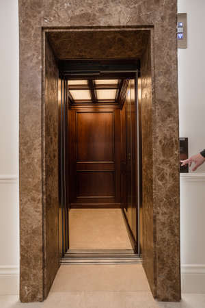 Wooden lift in business office building. Man push the buttonの写真素材