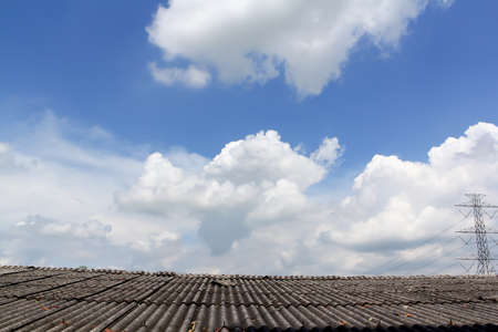 Cloudy sky on roof & high voltage towerの写真素材