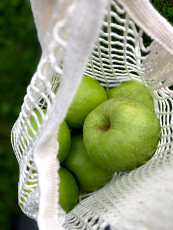 White string bag with lots of green apples - photoの写真素材