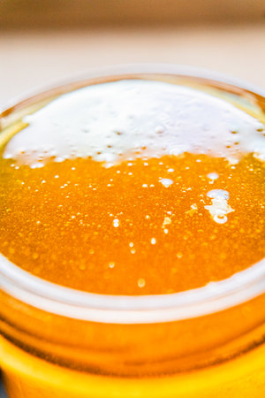 Sweet Golden Bee Honey with Bubbles Filled Into a Honey Jar Extreme Close Upの写真素材
