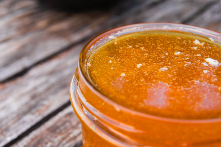 Honey Jar Filled to the Brim with Fresh Honey Standing on a Wooden Table Extreme Close Upの写真素材