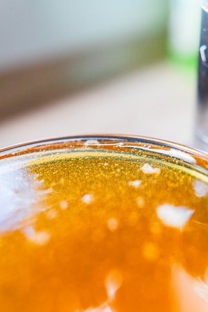 Sweet Golden Bee Honey Filled to the Brim of a Honey Jar Extreme Close Upの写真素材