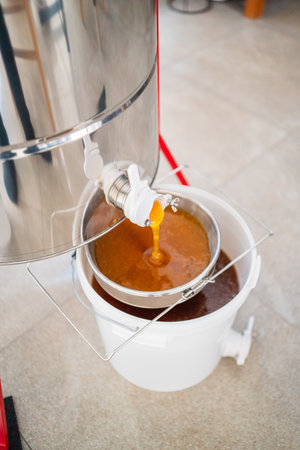 Beekeeping Honey Flowing Out of a Barrel Into the Sieve for Filtrationの写真素材