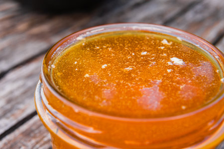 Honey Jar Filled to the Brim with Fresh Honey Standing on a Wooden SurfaceExtreme Close Upの写真素材