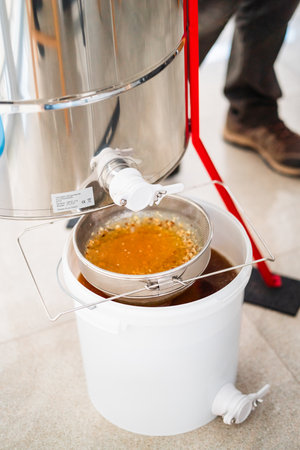 Centrifugal Extractor Barrel with First Filtered Batch of Honey in a Full White Bucketの写真素材