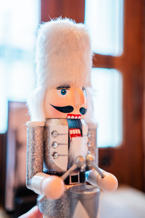 Decorative White Nutcracker With White Fur Bearskin Hat a Silver Costume and a Drum Standing on a Table With an Open Mouthの写真素材