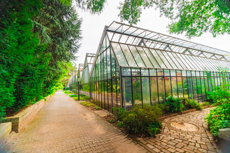 Glass Greenhouse Building in a Plantation for the Growth of Plants Flowers and Crops in Ecological Bio Sphere Garden Hatchery in Landscape Imageの写真素材