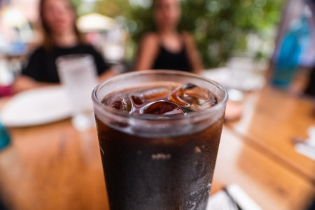 Cold Fresh Glass of Soft Drink Coke With Ice Cubes on a Wooden Table on a Hot Summer Dayの写真素材