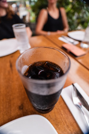 Cold Glass of Soft Drink Coke With Ice Cubes on a Wooden Tableの写真素材