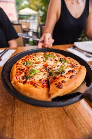 Vegetarian Broccoli Pizza in a Frying Pan Freshly Baked Coming From the Oven Taking a Slice of Pizza With Cheese and Broccoliの写真素材
