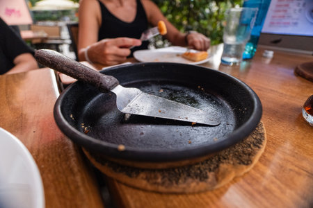 Empty Frying Pizza Pan With Metal Spatula on a Wooden Table in a Restaurantの写真素材