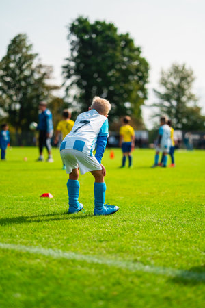 Young Football Player in White and Blue Jersey Standing on the Sideline Waiting to be Activatedの写真素材