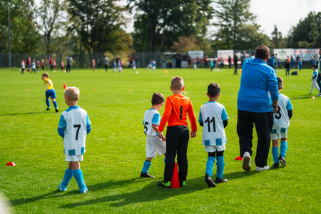 Team of Young Child Soccer Players Standing on the Football Field with their Trainer Ready to Playの写真素材