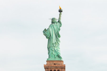 Statue of Liberty from behind looking into the sky of clouds representing its landmark statue in New York Cityの写真素材